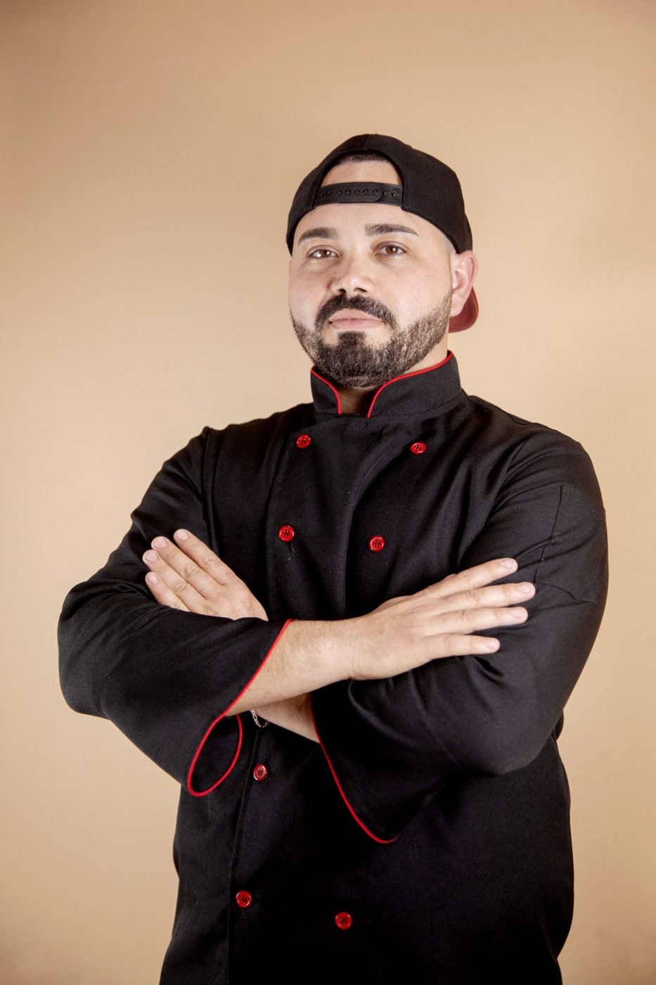 Chef Weslei Vigolo de dólmã preto, de braços cruzados